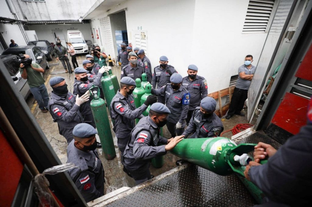 Policiais militares carregam cilindros de oxigênio